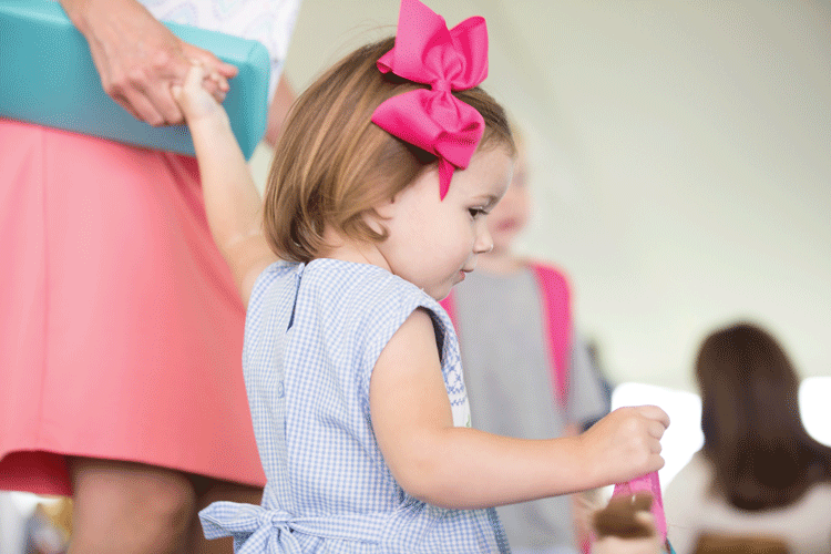France Bognon's daughter, Isla, models a smocked blue gingham dress by Sweet Dreams and a charming pink bow by Wee Ones, both from The Fun Shop