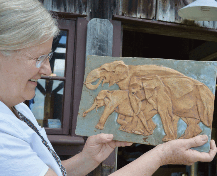 Joan Gardiner holding one of her relief tiles